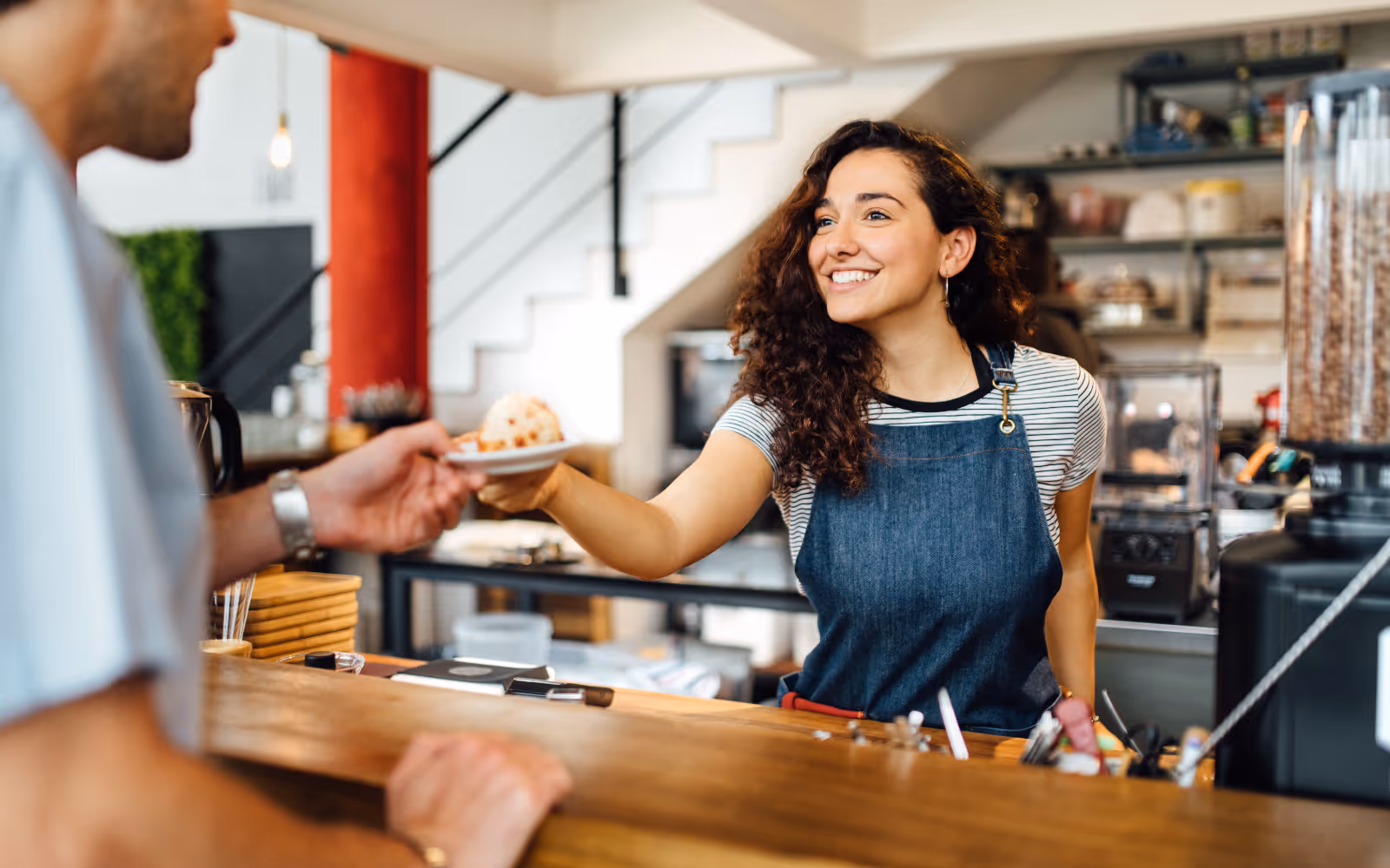 a barista handing a muffin to a surprised customer